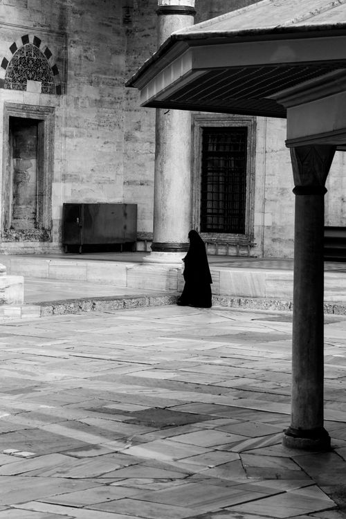 Free A person in traditional attire stands alone in the courtyard of a historic mosque in Istanbul. Stock Photo
