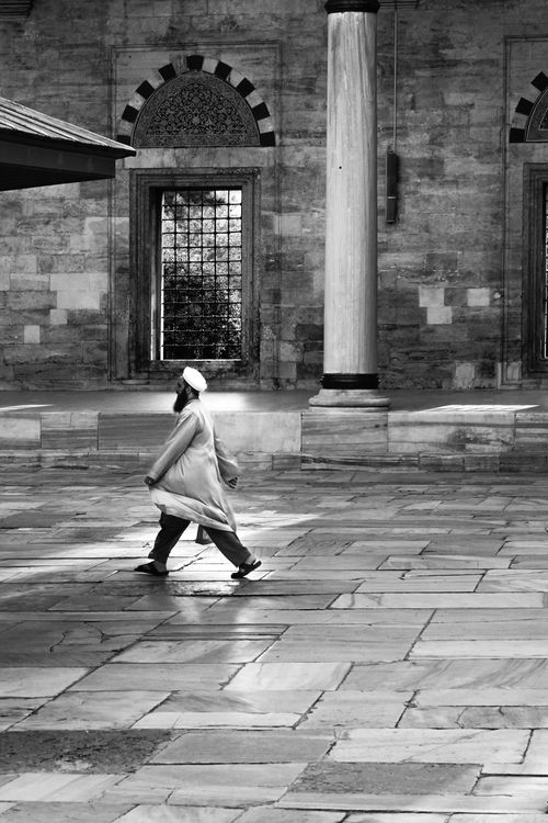 Free A man in traditional attire walks past historical architecture in Istanbul. Stock Photo