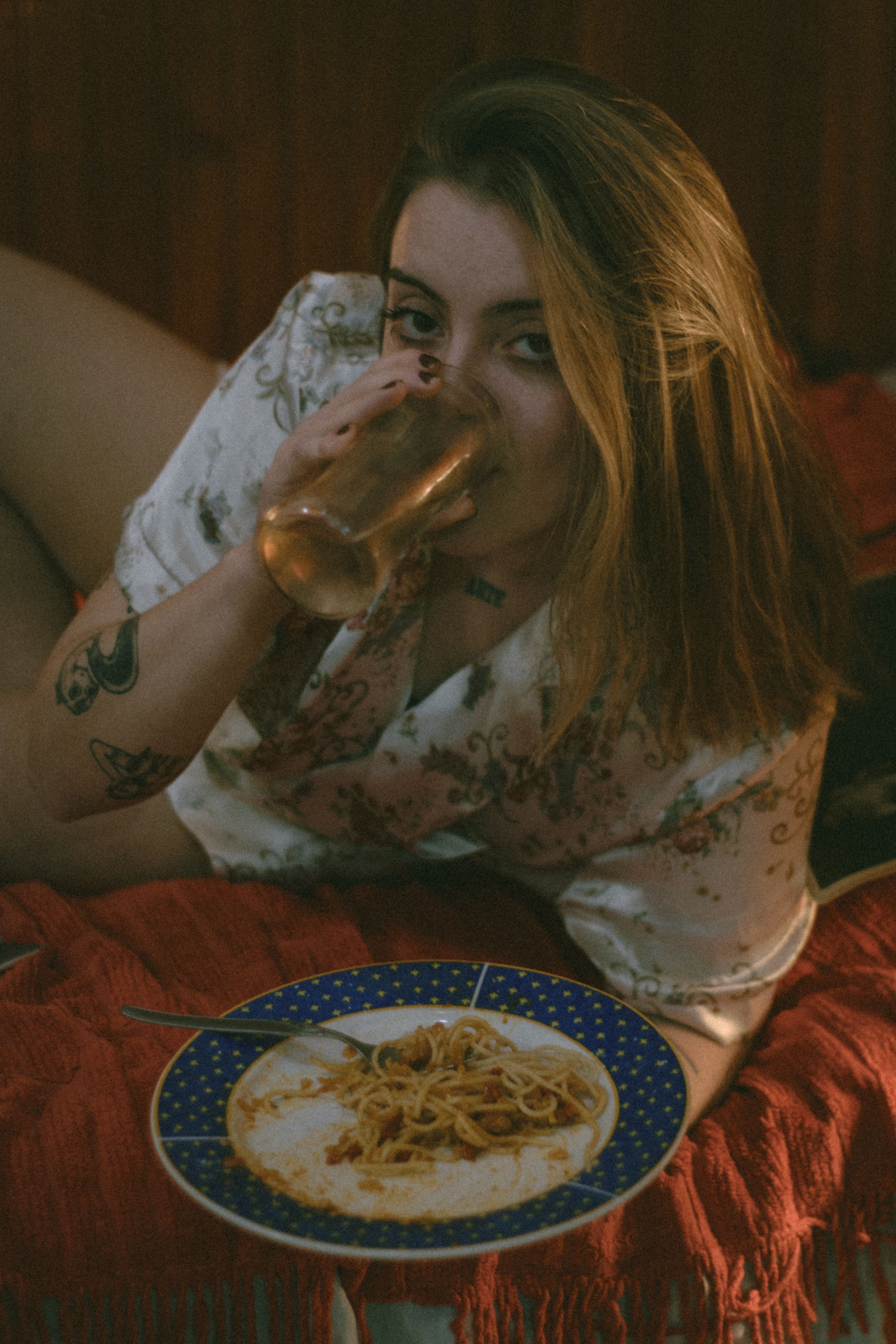 Fotomural Mujer tumbada en posición relajada disfrutando de una comida y una bebida en un ambiente hogareño acogedor.