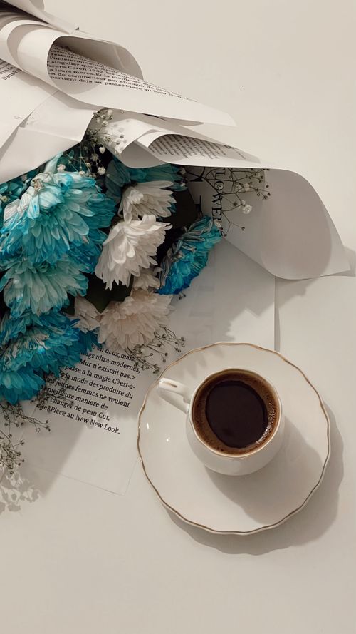 Free An elegant arrangement of blue and white flowers with a cup of coffee on a light background. Stock Photo