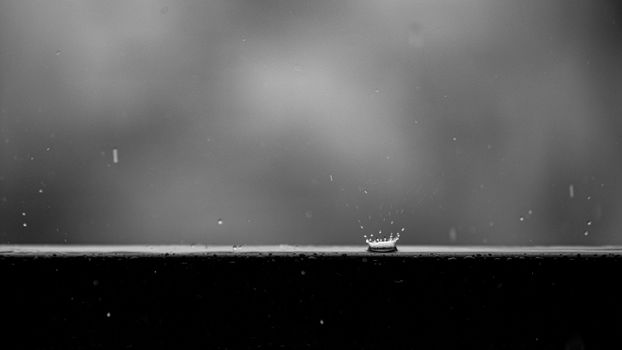 Black and white macro shot of a water droplet splashing on a surface, creating a crown-like effect.