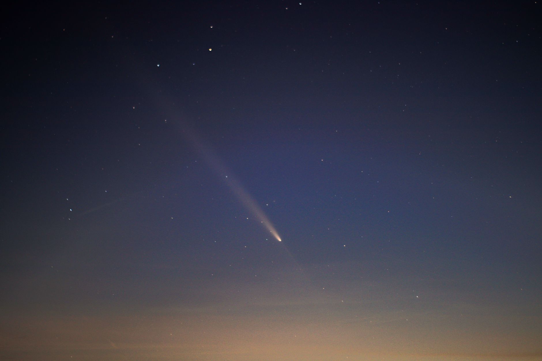 Captivating view of a comet streaking across the night sky with twinkling stars.