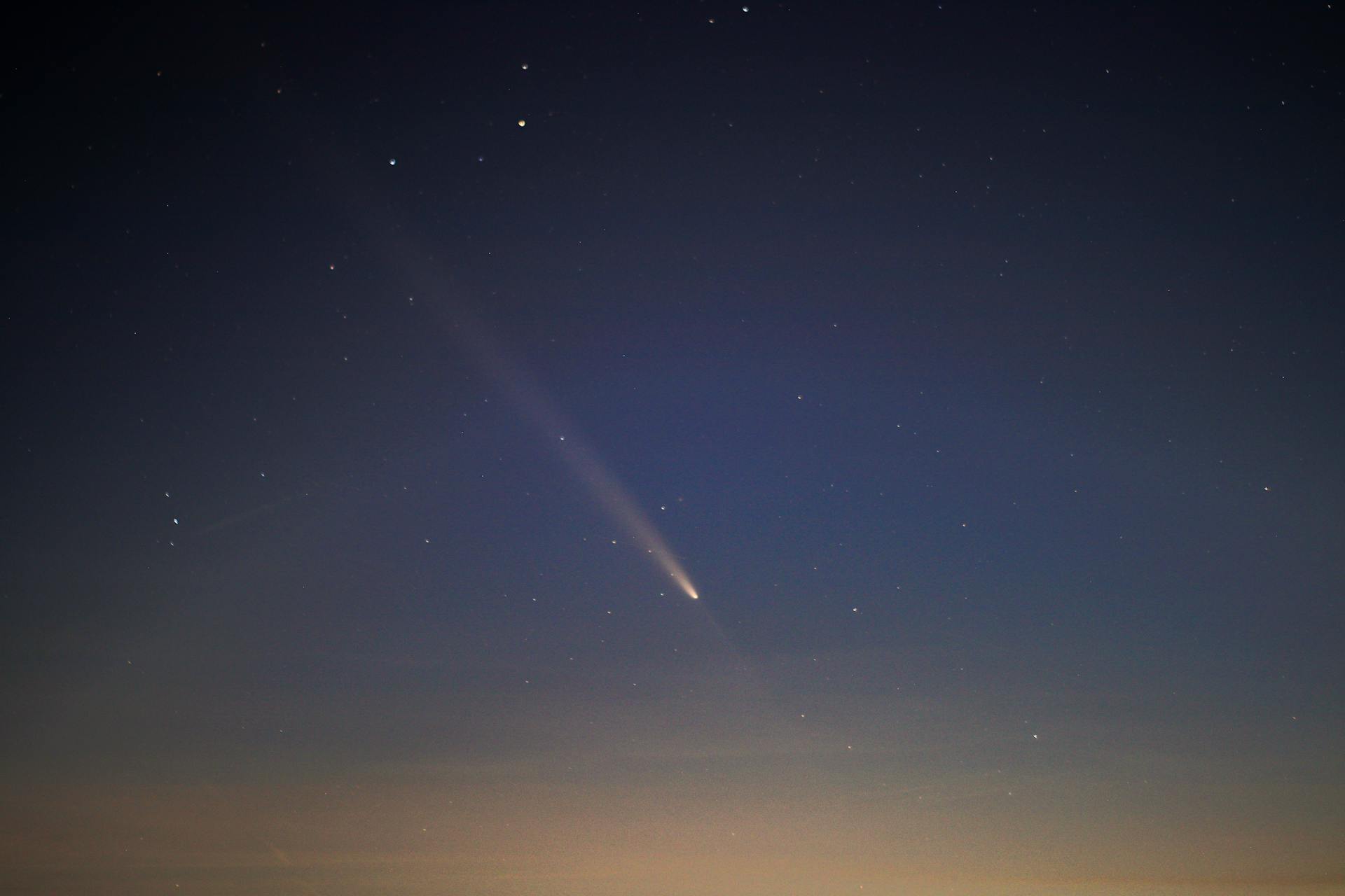 Captivating view of a comet streaking across the night sky with twinkling stars.