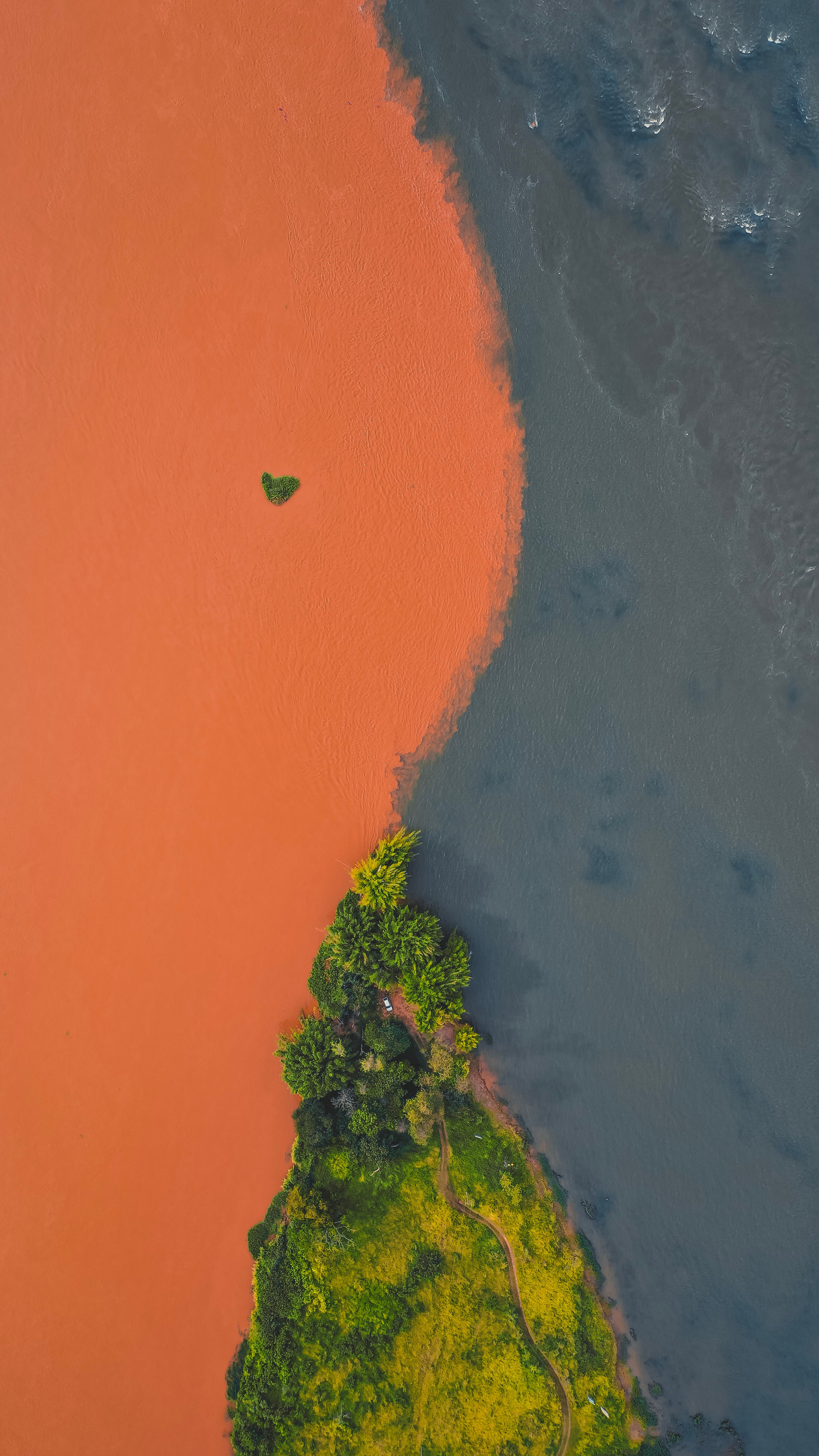 Aerial photo showcasing a vibrant river confluence with lush greenery and contrasting water colors.