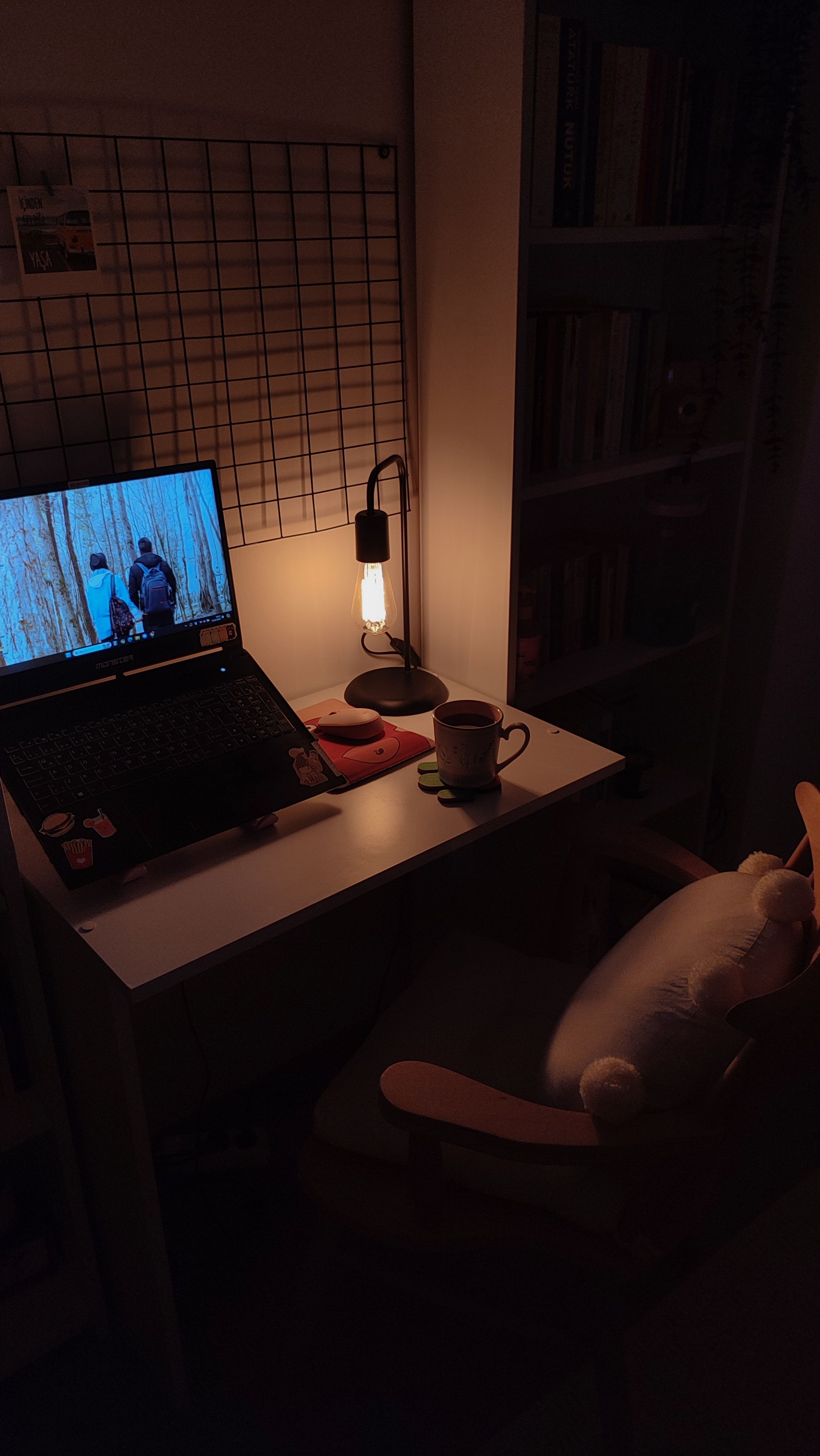 A cozy home office desk with a warm lamp, laptop, and books, creating a tranquil atmosphere.