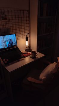 A cozy home office desk with a warm lamp, laptop, and books, creating a tranquil atmosphere.