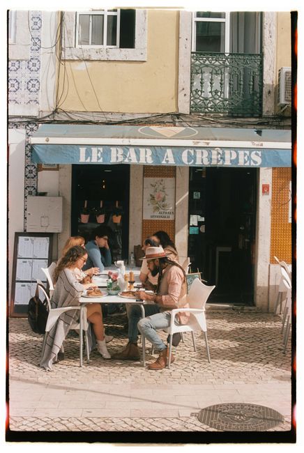 Visitors enjoy outdoor dining at Le Bar à Crêpes in sunny Lisbon, Portugal.