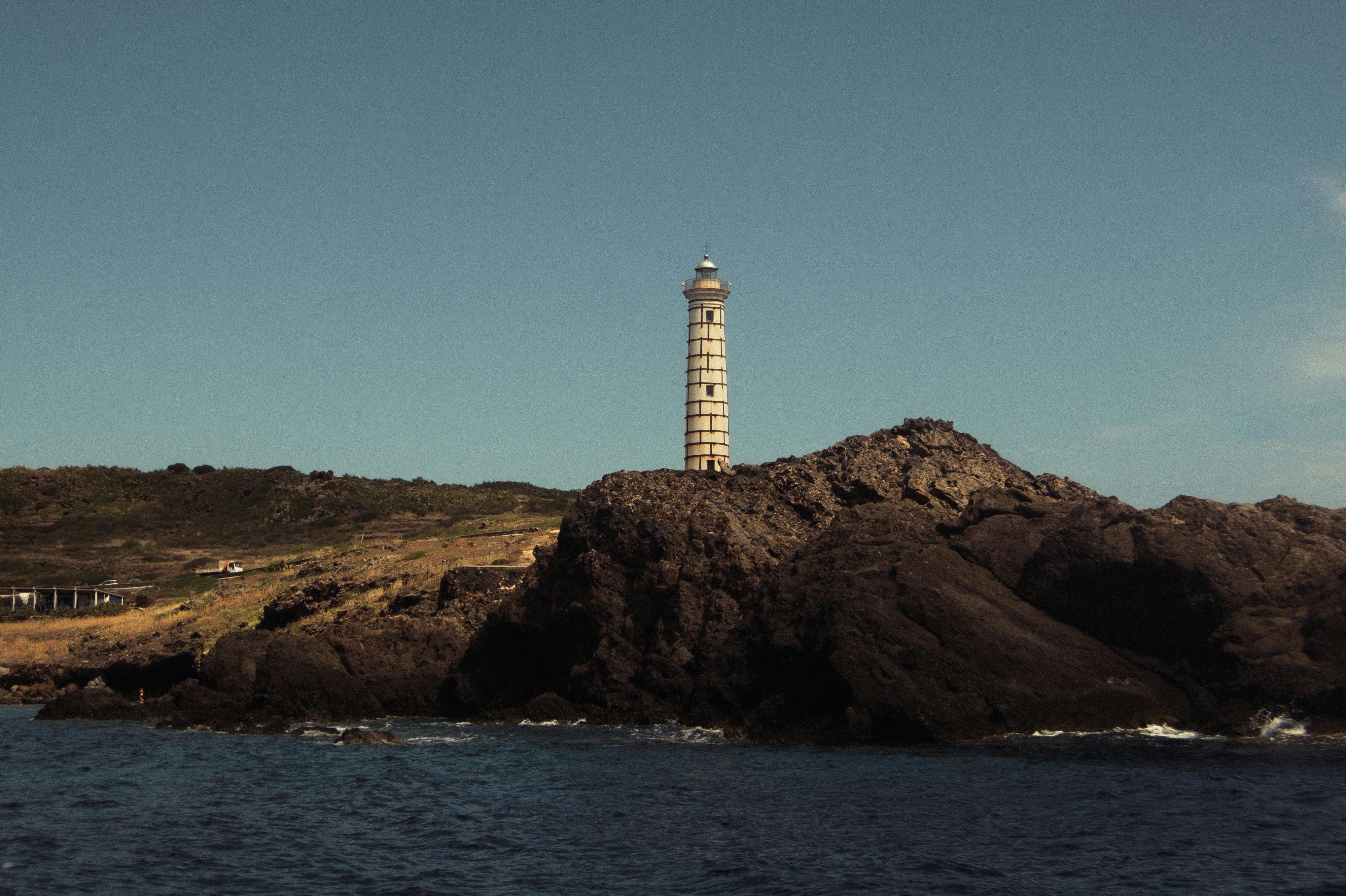 Beautiful lighthouse standing on rocky coast of Ustica Island, Sicily under a clear summer sky.