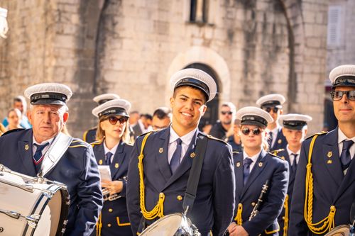 Free A vibrant marching band performing outdoors in a historic town setting, dressed in crisp uniforms. Stock Photo