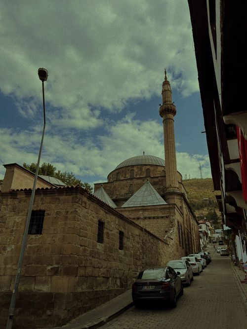 Free Old stone mosque and tall minaret under vibrant blue sky on a narrow street. Stock Photo