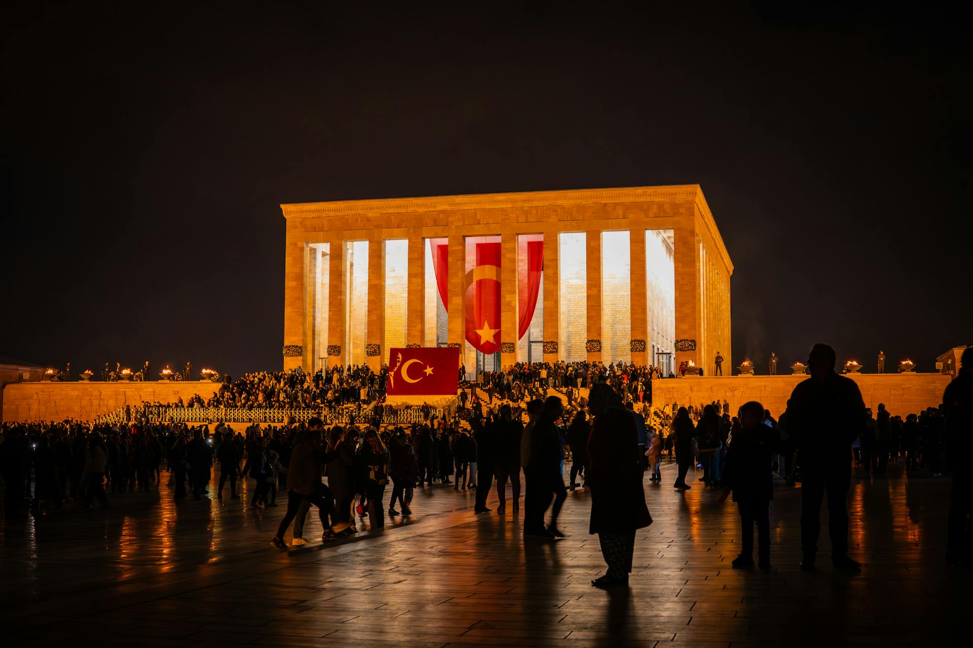 A vibrant nighttime scene at Anıtkabir in Ankara, Türkiye, with a crowd of people gathered outdoors.