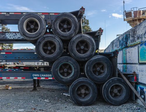 Free Row of stacked truck tires on chassis in an industrial area. Stock Photo