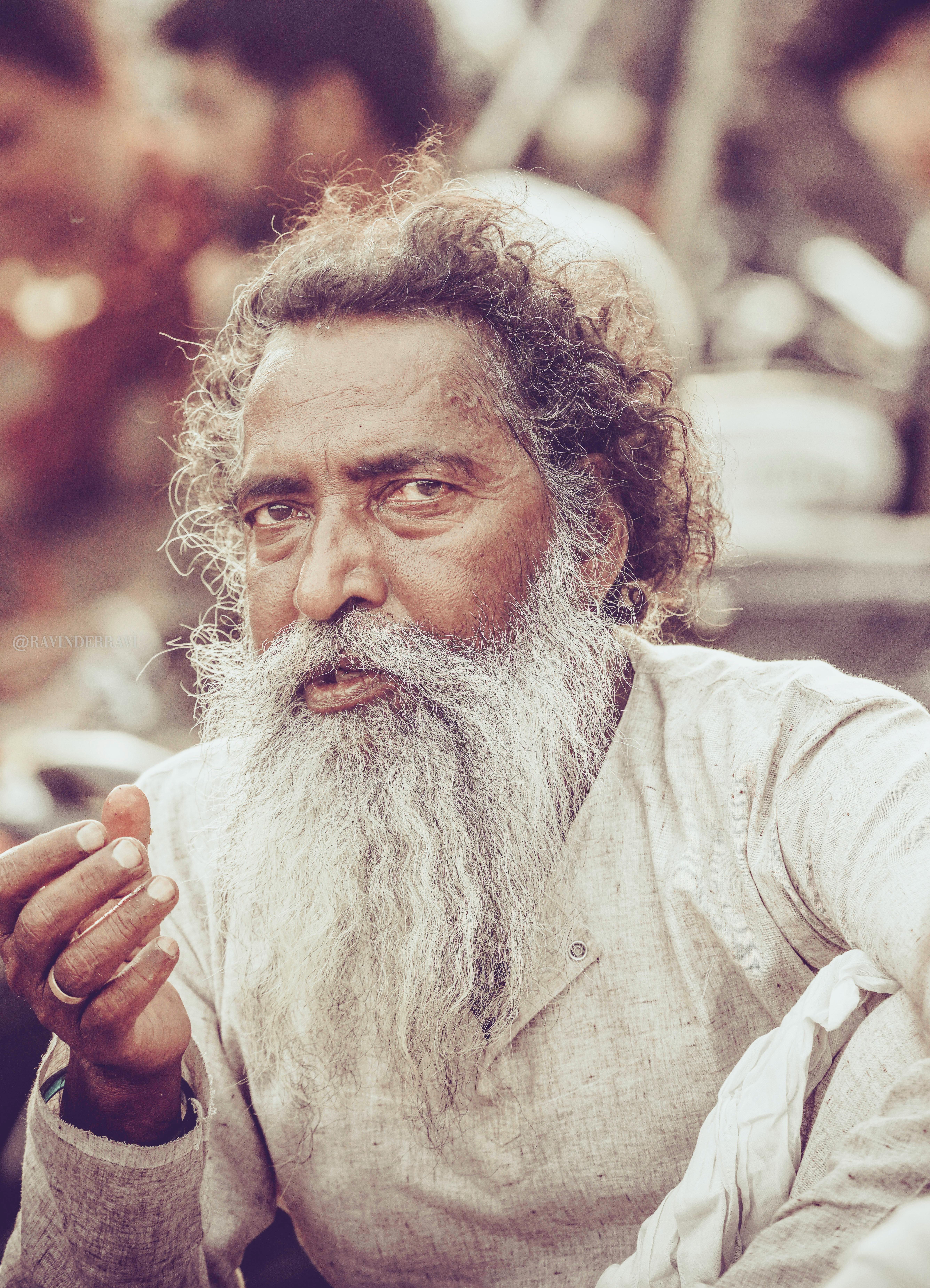 Close-up of an elderly man with a long beard, capturing his thoughtful expression outdoors.
