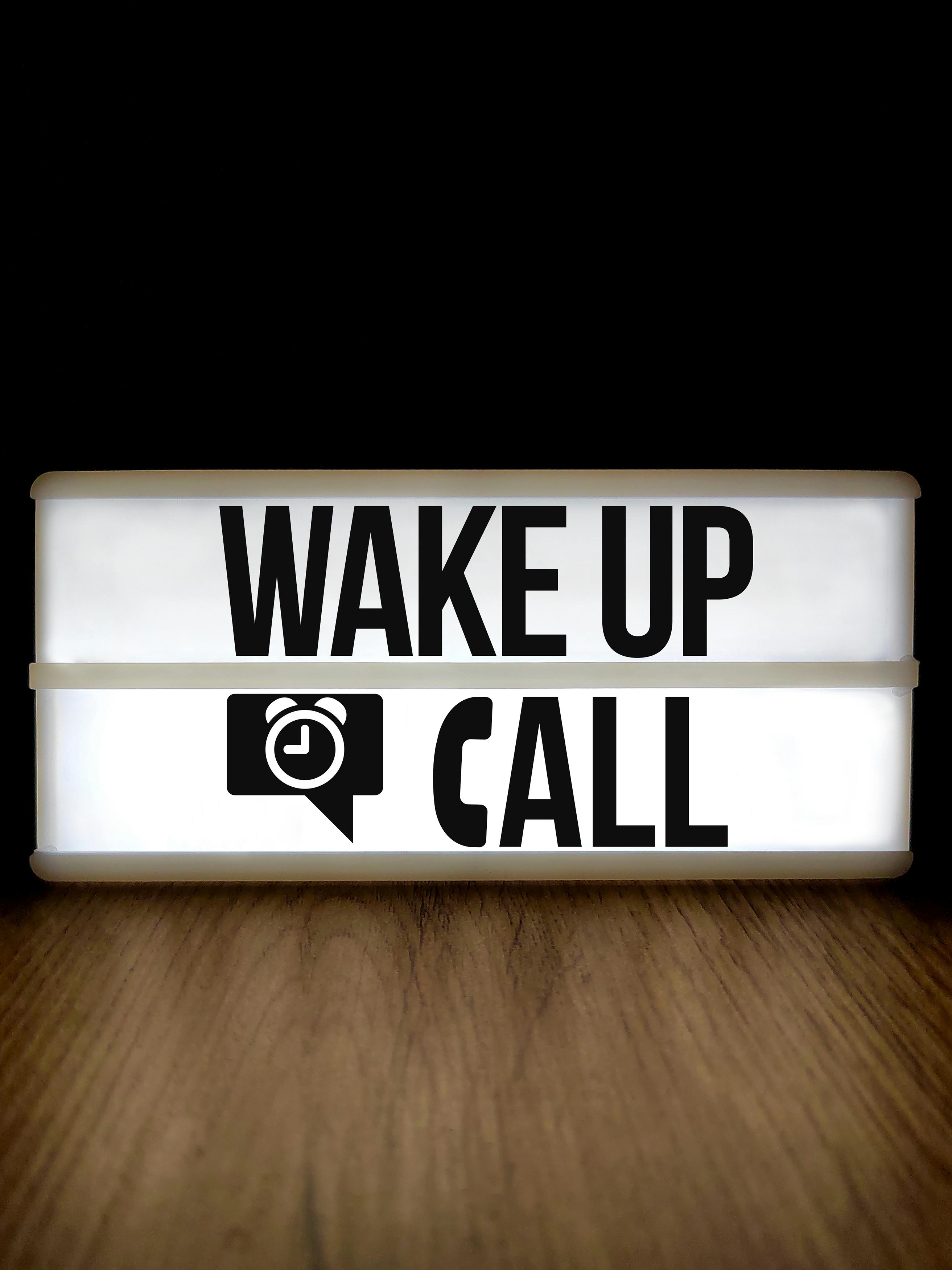 Ücretsiz Siyah bir arka plan üzerinde ahşap bir yüzey üzerinde 'Uyanış Çağrısı' yazısını gösteren parlak ışık kutusu. Stok Fotoğraflar