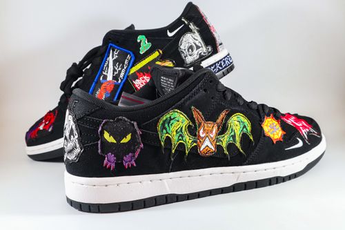 Free Black sneakers featuring colorful embroidered patches and unique designs on a white background. Stock Photo