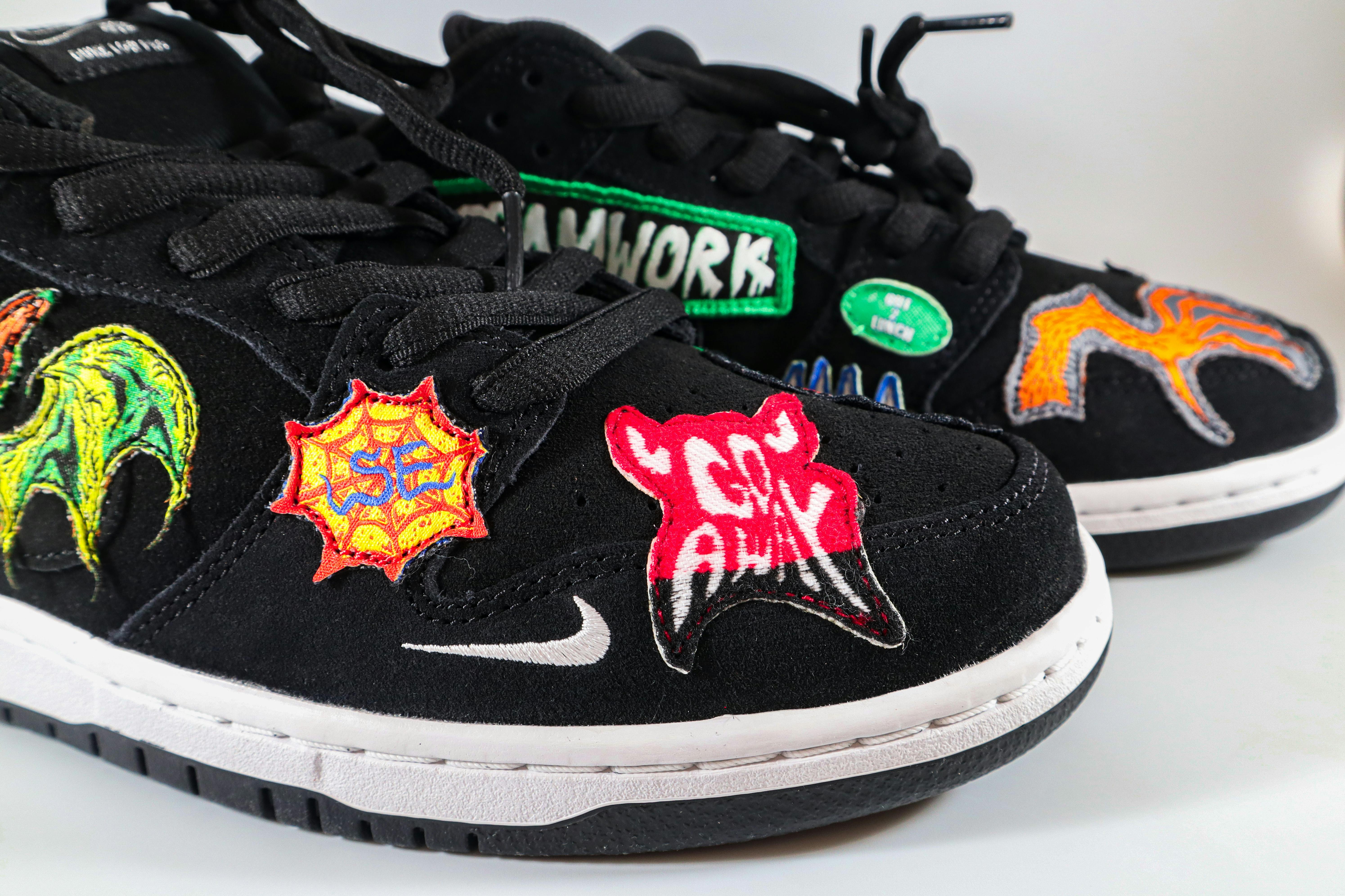 Trendy black sneakers embroidered with vibrant patches, perfect for streetwear fashion.