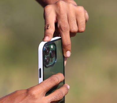 Hands holding a smartphone outdoors, capturing a moment with precision and focus.