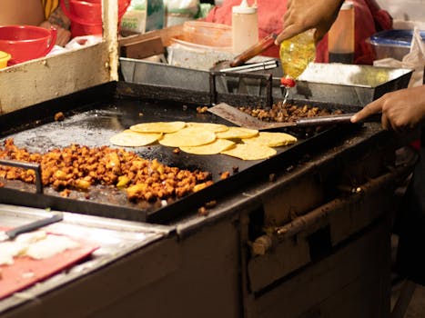 Men cooking authentic Mexican tacos at a street food stand in Mexico City.