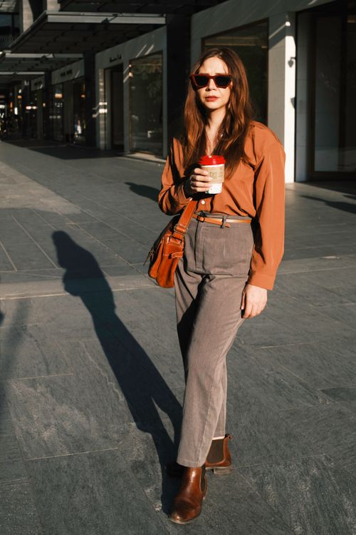 Free Stylish woman wearing sunglasses and holding coffee in a modern city environment. Stock Photo