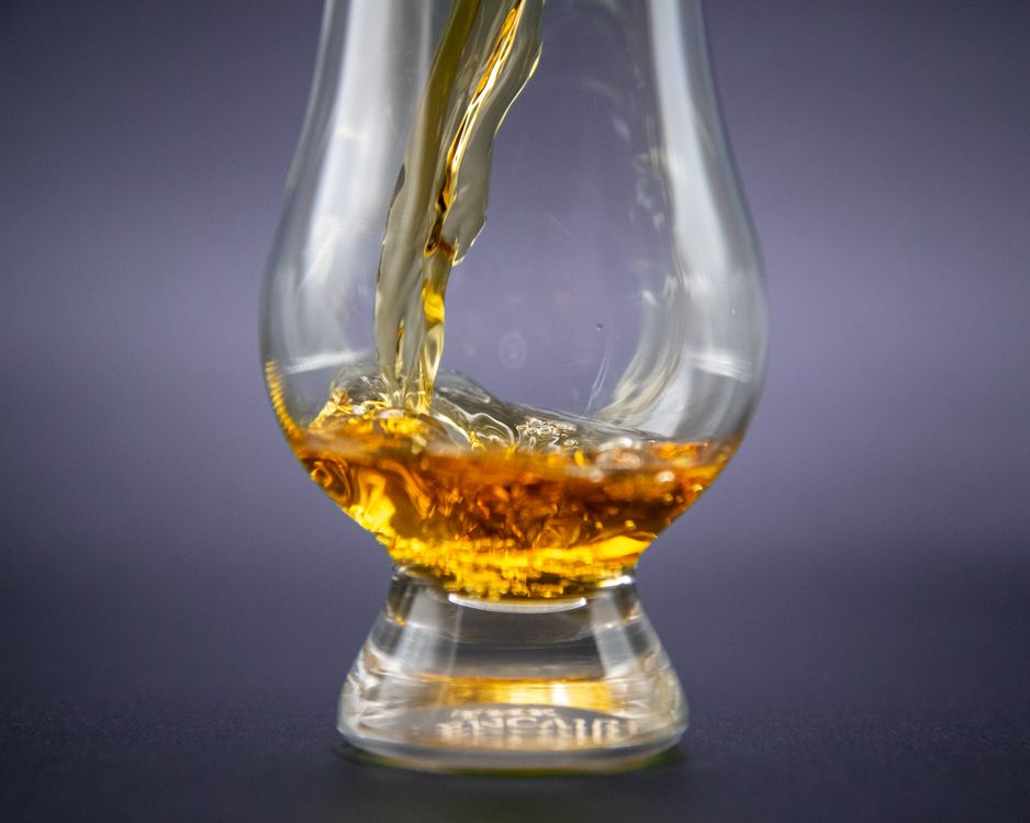 Golden whiskey slowly poured into an elegant glass