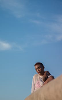 一名女子在户外，对着充满活力的蓝天摆姿势，捕捉着宁静沉思的瞬间