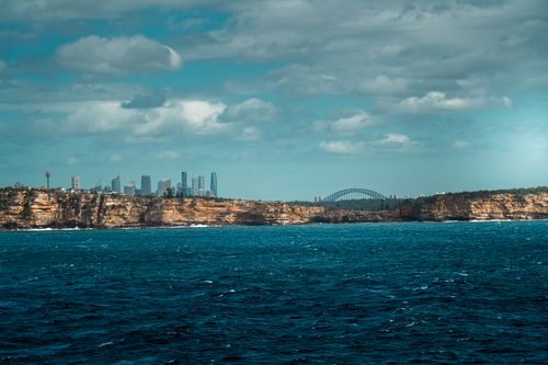 Free Dramatic coastal cliffs with the Sydney skyline and Harbour Bridge in the background. Stock Photo