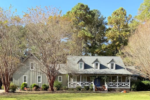 A picturesque ranch-style house surrounded by autumn trees and greenery.