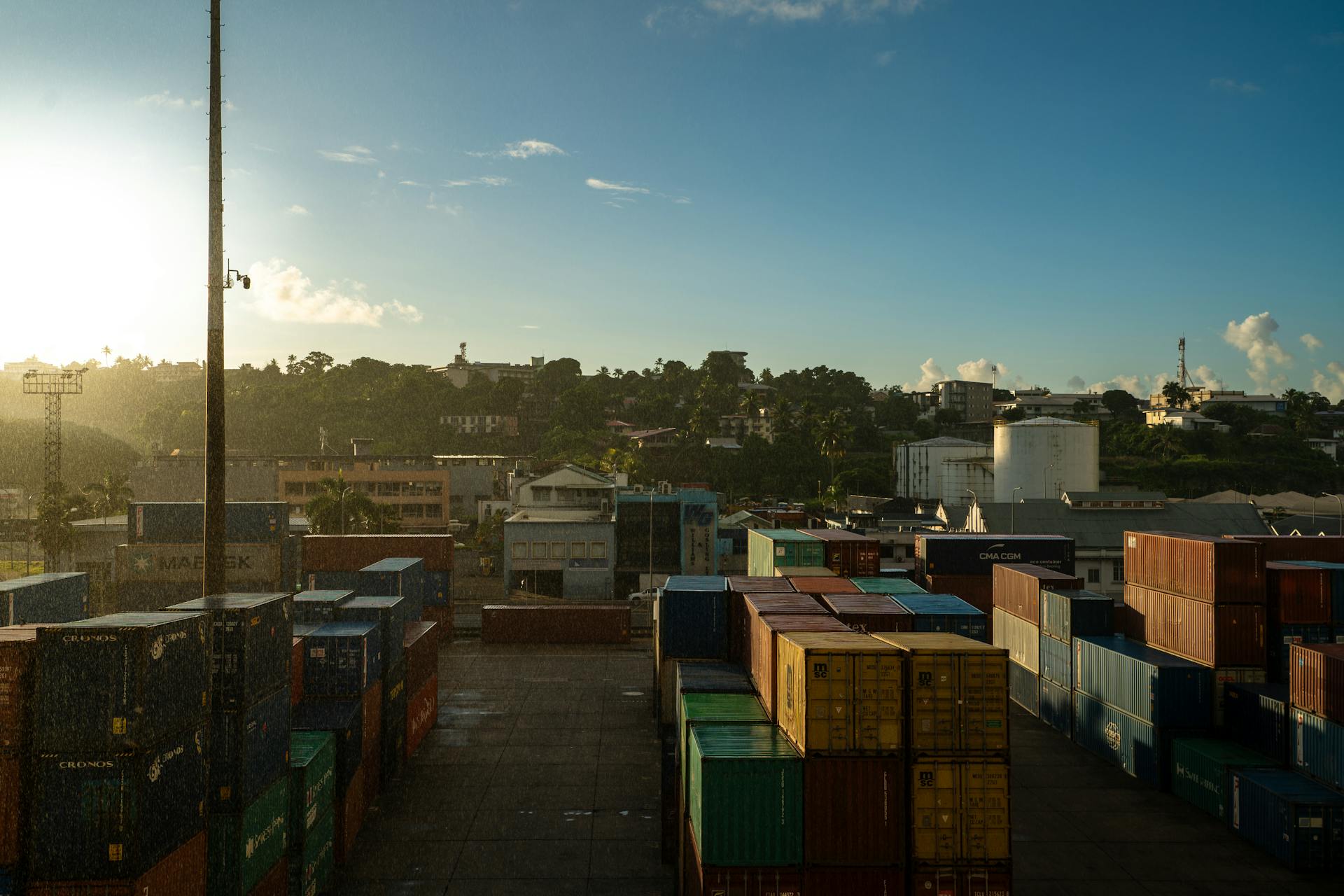 Shipping containers at Suva port in Fiji with sunrise, showcasing a vibrant industrial landscape.