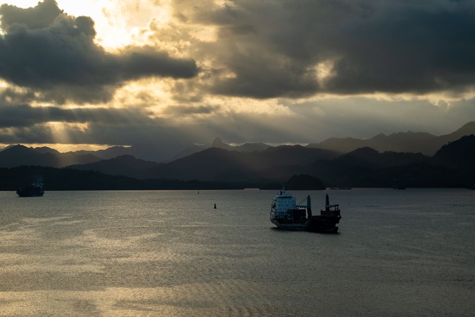 Stunning view of a cargo ship in Fiji at sunset with majestic mountains.