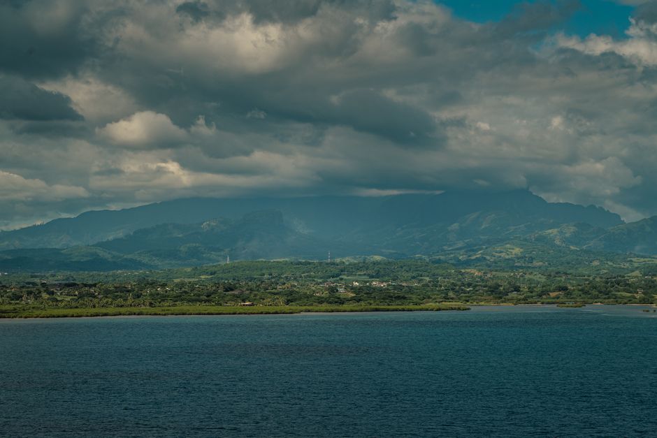Explore the stunning landscape of Suva with lush mountains and the Pacific Ocean under a cloudy sky.
