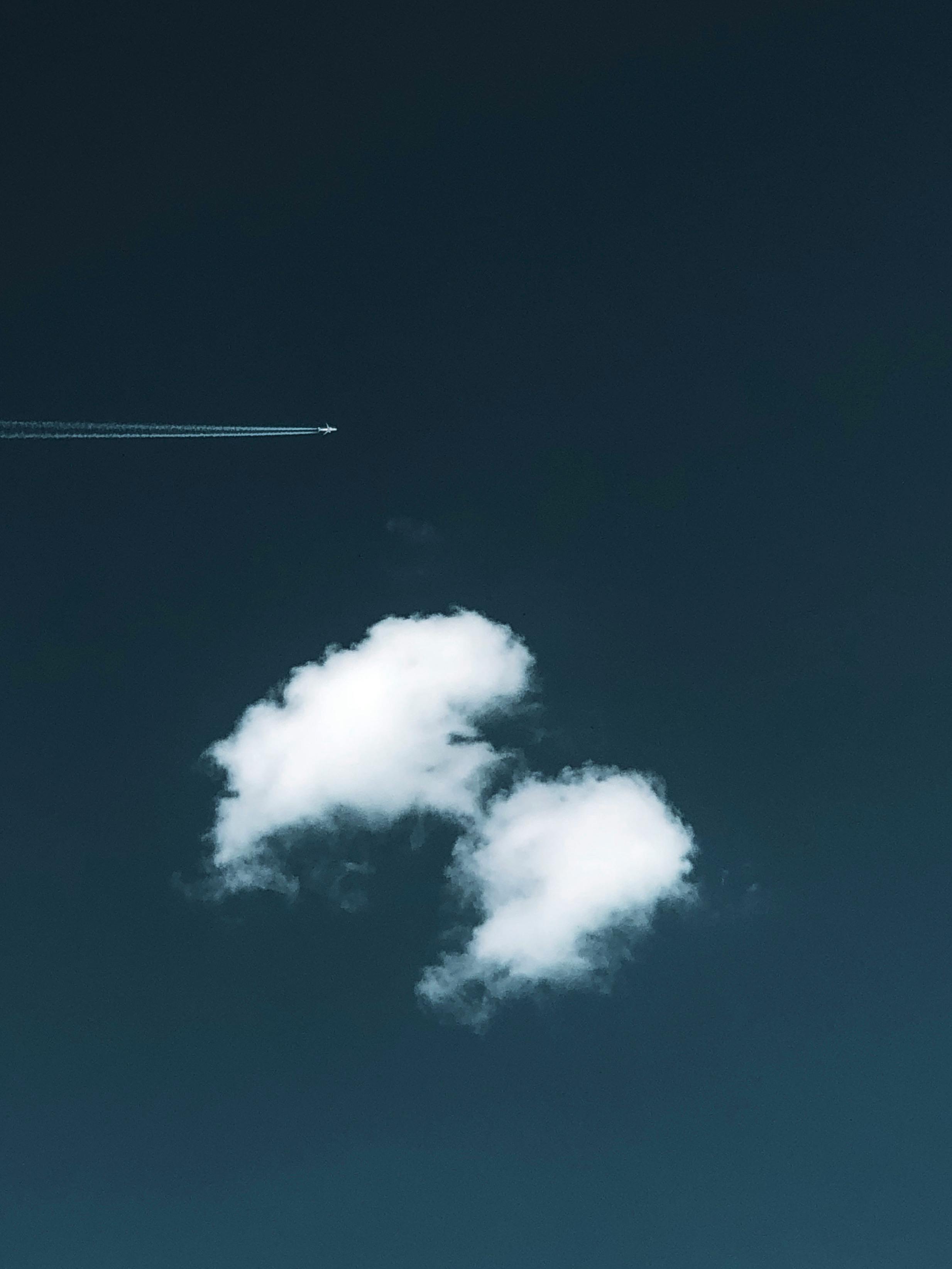 Kostenlos Luftaufnahme eines klaren Himmels mit Kondensstreifen eines Flugzeugs und flauschigen Wolken. Stock-Foto