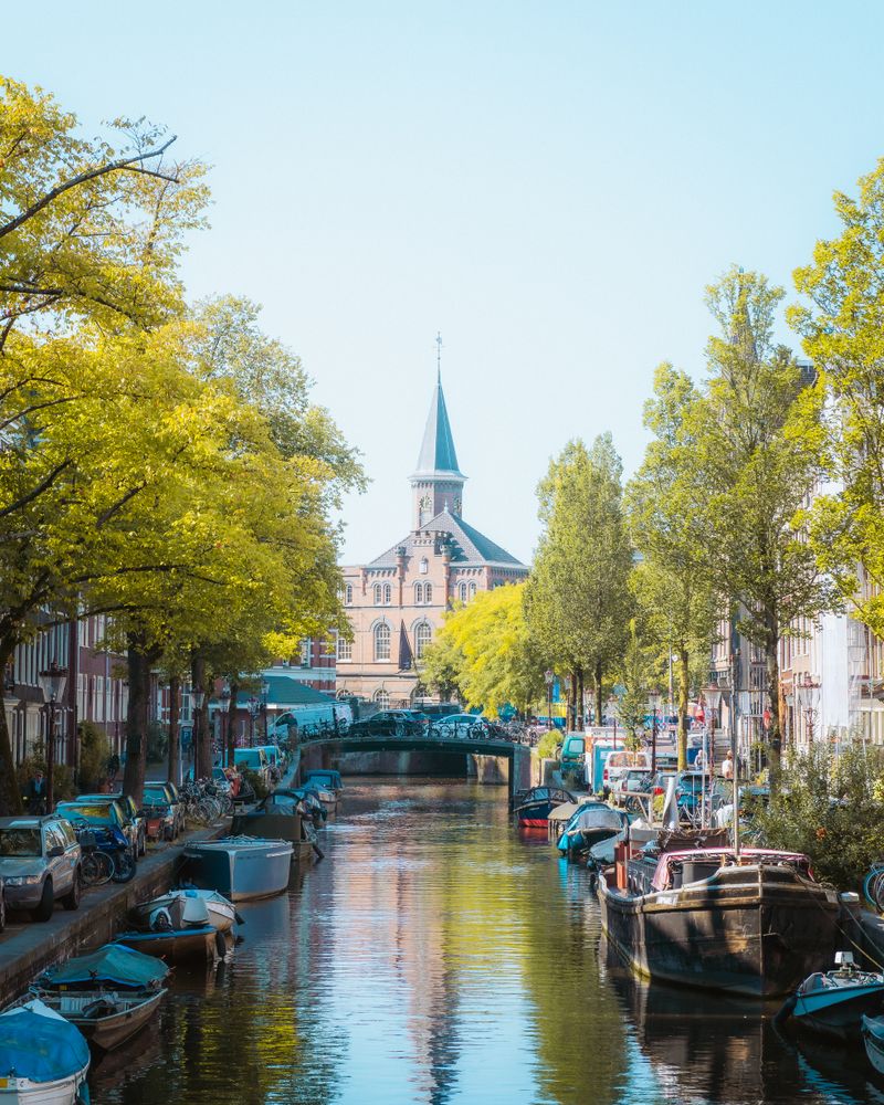 A tree-lined canal in the Jordaan with traditional houses and the Westerkerk spire