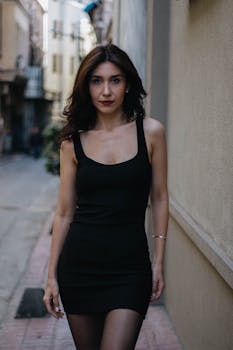 Fashionable woman in a black dress walking through a narrow Istanbul alleyway, showcasing urban style and grace.