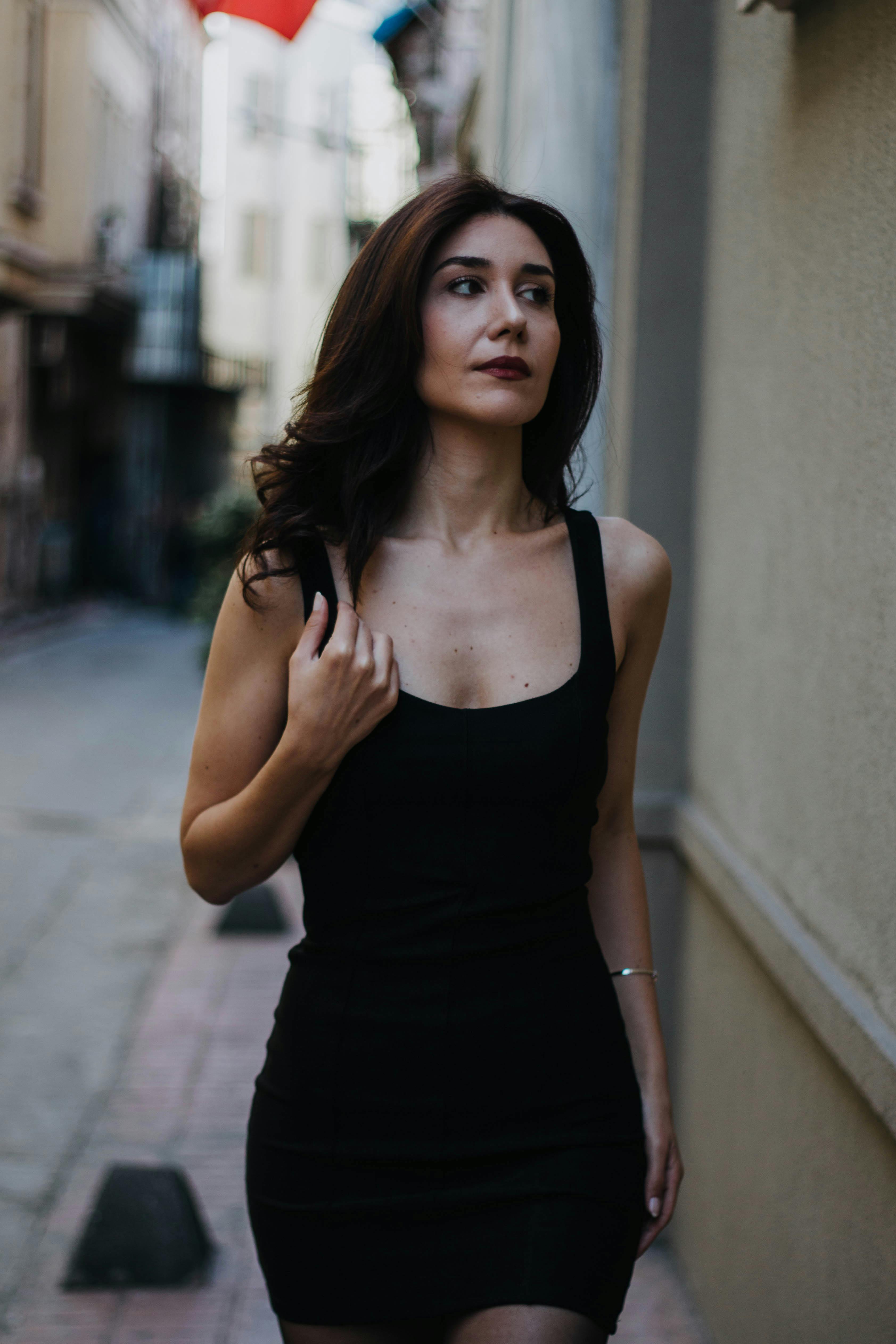 bezplatná Okouzlující žena v černých šatech procházející se uličkou Istanbulu, odrážející moderní módu. Základová fotografie