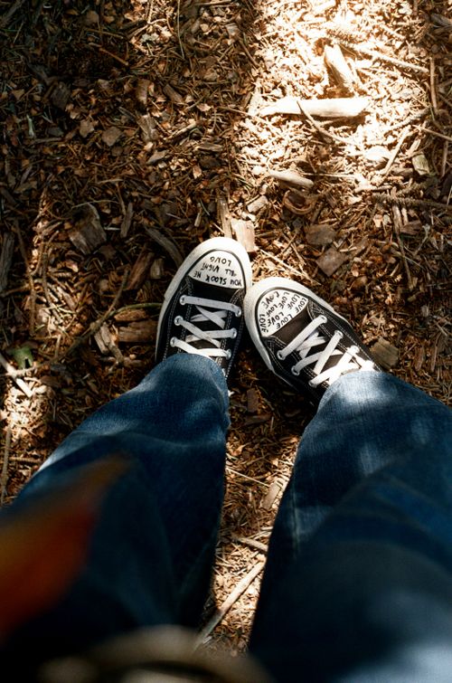 Free A pair of black and white sneakers in the forest, lit by sunlight filtering through trees. Stock Photo