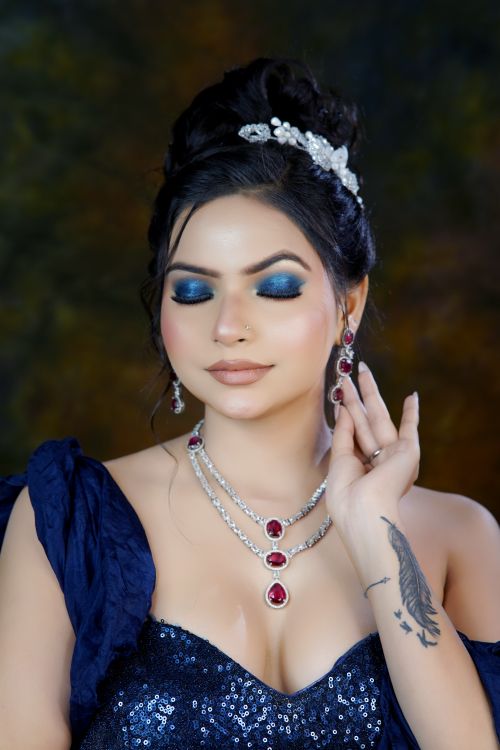 Free Close-up portrait of a woman wearing striking blue eyeshadow and elegant silver jewelry with red gemstones. Stock Photo
