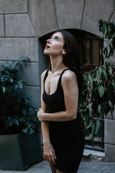 A woman in a black dress poses stylishly on a street in Istanbul.