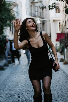 Woman in black dress joyfully walking through picturesque Istanbul street.