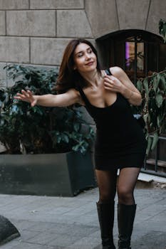 Charming young woman in a black dress happily posing on a street in Istanbul, Türkiye.