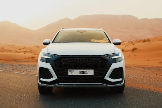 Stunning view of a luxury SUV on a desert road at sunset with scenic sand dunes in the background.