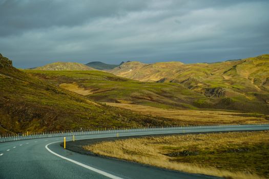Curving road through the mountainous landscape of Iceland, showcasing autumn colors.