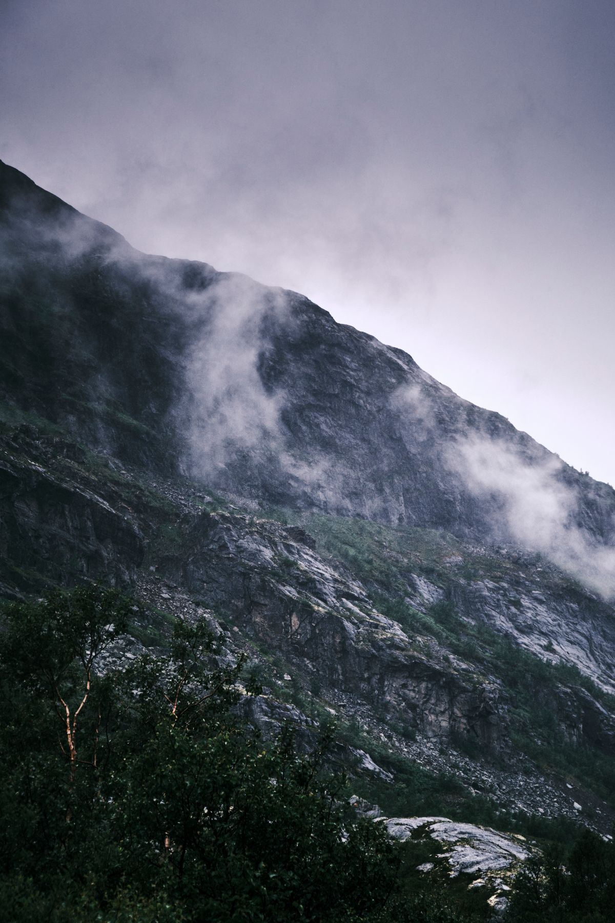 Mist gathering over a lone mountain ridge in low light