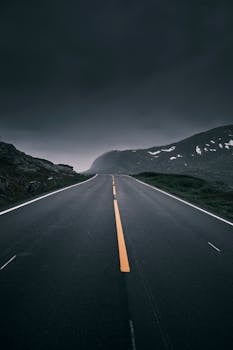 Empty mountain road under ominous dark skies, perfect for travel themes.