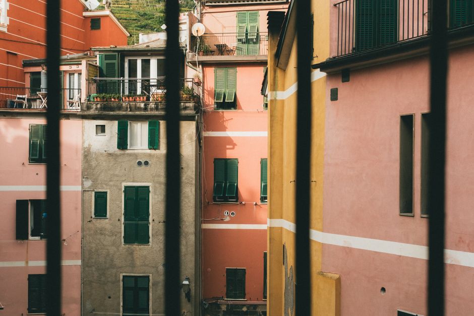 Colorful buildings in Vernazza captured through a balcony railing.