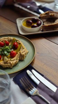 Mediterranean hummus with tomatoes and olives on a rustic table setting.