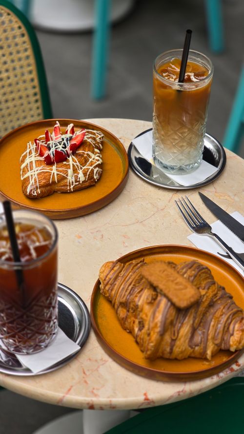 Free Table with iced coffee, croissant, and pastry at a cozy cafe setting. Stock Photo