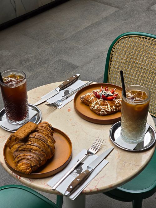 Free Two iced coffees with pastries on a small round table outdoors. Stock Photo