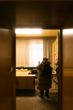 Person in a warm coat photographing inside a vintage office with wooden accents.