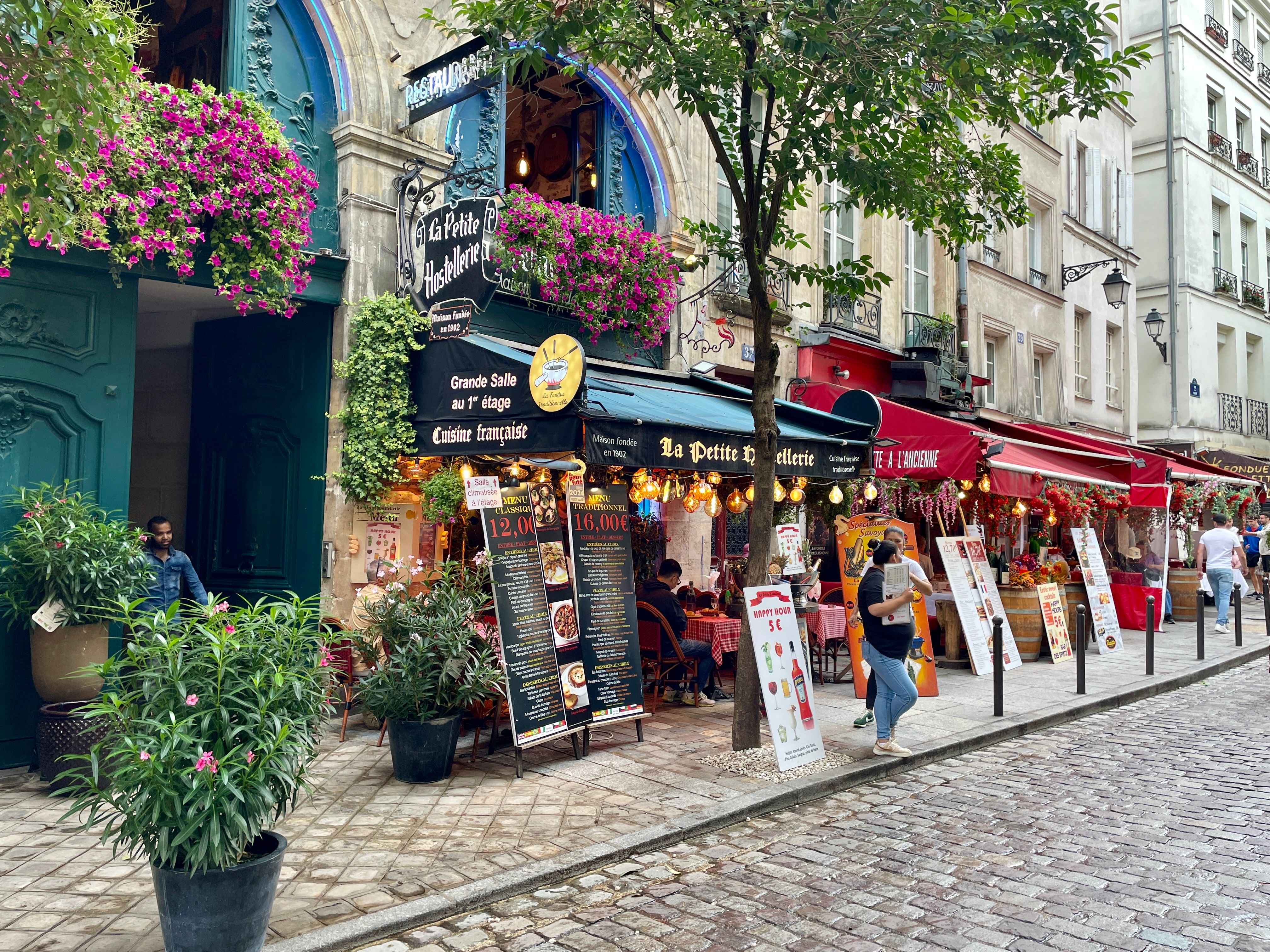 Delightful street view of Parisian cafes with vibrant flowers on a summer day.