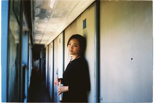 Free A young woman standing in a train corridor, gazing thoughtfully. Stock Photo